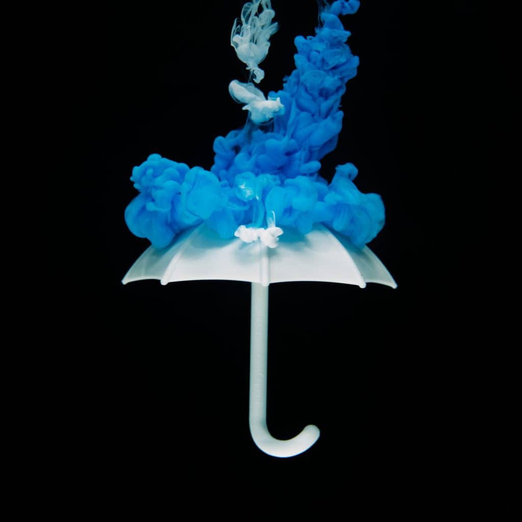 white umbrella being hit with blue smoke splash